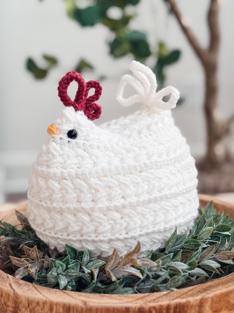 Wheat Stitch Chickens crochet pattern: white crochet chicken with braided texture and red comb sitting in a wooden bowl of greenery