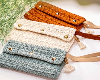 May include: Three crocheted clutches with leather straps and tassels. The clutches are in shades of orange, cream, and blue.