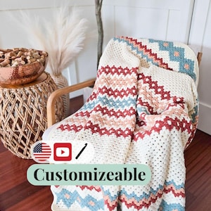 May include: A cream-colored, crocheted blanket with a geometric pattern in red, blue, and peach tones is draped over a wooden chair. The blanket features the word "Customizable" in a banner.