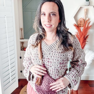 A woman wearing a vintage crochet sweater paired with a pink skirt, accessorized with unique handmade jewelry.