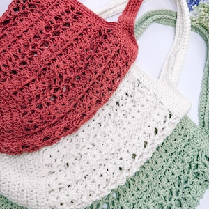 Puede incluir: Tres bolsas de mano de crochet en rojo, blanco y verde. Las bolsas tienen un patr&oacute;n de red y asas largas. Las bolsas est&aacute;n hechas de un hilo suave y texturizado, perfectas para llevar comestibles u otros art&iacute;culos.