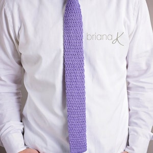May include: A white dress shirt with a lavender knitted tie. The tie has a textured pattern.