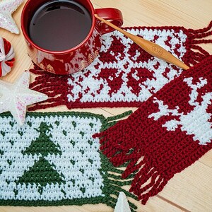 May include: Three crocheted coasters with fringe, featuring a Christmas tree, reindeer, and snowflake designs. The coasters are in red, green, and white yarn.
