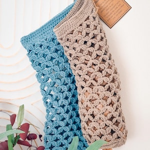 May include: Two crochet plastic bag savers, one blue and one beige, featuring an openwork lattice pattern. A brown paper tag attached to the beige bag reads: Plastic Bag Saver, Stuff 'em in the top, pull 'em from below, your plastic bags now have a place to go!