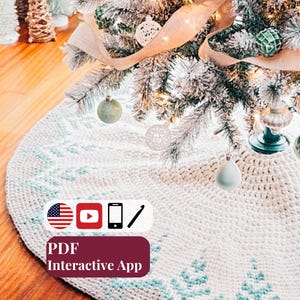 May include: A round, cream-colored crocheted Christmas tree skirt featuring a light blue geometric pattern along the border. The image includes icons for the US flag, YouTube, a smartphone, a crochet hook, and text reading PDF Interactive App.