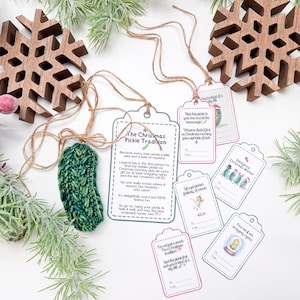 May include: A green knitted pickle ornament with a brown twine string, accompanied by several white paper gift tags featuring illustrations of pickles and text explaining The Christmas Pickle Tradition, including spaces for to and from names.