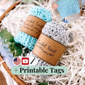 以下が含まれることがあります： バスケットには、水色とグレーの2つの丸められたかぎ針編みの鍋敷きが入っています。それぞれに「Crochet Trivet」と書かれた茶色の紙バンドが巻かれています。水色のかぎ針編みの正方形と「+ Printable Tags」の文字も表示されています。