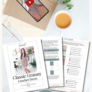 Flat lay image featuring a PDF pattern for a crochet dress, a smartphone displaying the dress, a cup of tea, an envelope, and green foliage. The scene has a charming vibe reminiscent of vintage clothes and makes for an exquisite handmade gift.