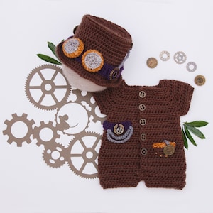 May include: A brown crocheted baby outfit with short sleeves and a matching brown crocheted hat. The outfit has a steampunk theme with gears, buttons, and a pocket. The hat has a purple band and two goggles.