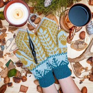 May include: A pair of teal blue and yellow knitted mittens with a geometric pattern. The mittens are on a wooden surface with various natural items.