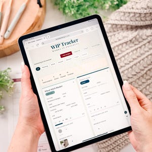 Könnte beinhalten: Ein Tablet mit einer digitalen WIP-Tracker-Oberfläche zur Verwaltung von Handarbeitsprojekten. Der Bildschirm zeigt Projektkategorien, einen Eintrag für eine Wheat Stitch Blanket mit Fortschrittsbalken, Garninformationen und ein Foto-Thumbnail.