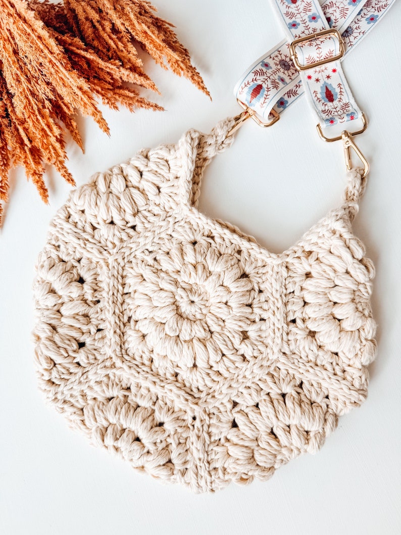 A cream crochet bag on a white background with fall foliage in the corner
