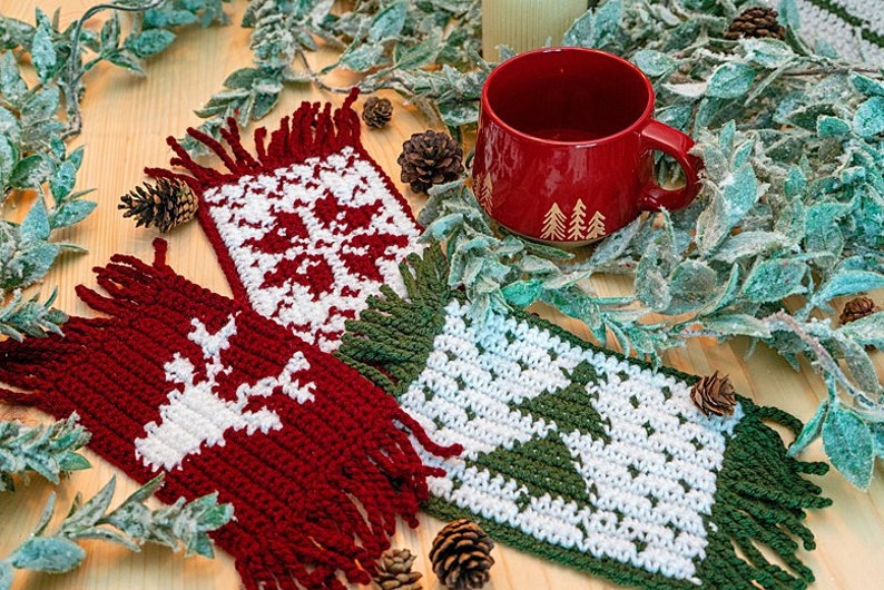 May include: Three crocheted coasters with festive winter designs. The coasters are red, green, and white with snowflake, reindeer, and Christmas tree patterns.