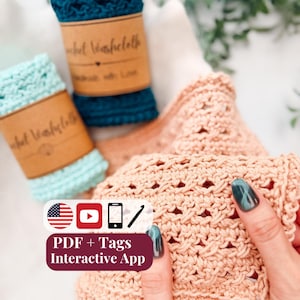 May include: Three crocheted washcloths in teal, light blue, and peach, each featuring a textured openwork pattern. Two are rolled with brown paper labels reading Crochet Washcloth, while the third is held open to display the stitch detail.