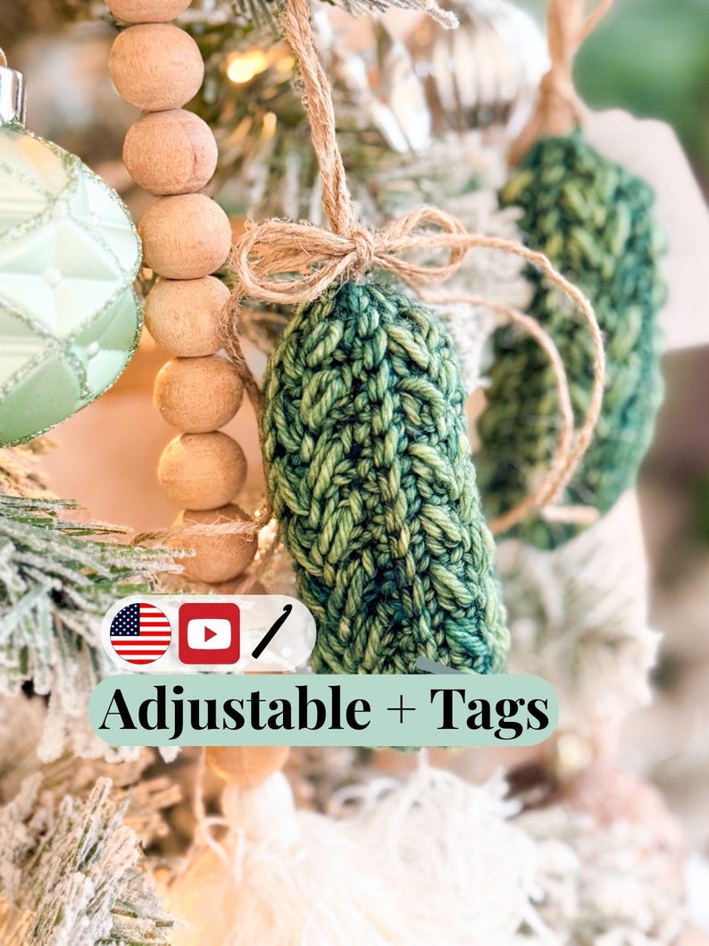 May include: A green crocheted ornament shaped like a pickle, featuring a textured yarn pattern and a tied jute twine loop for hanging. The image includes a graphic with the text Adjustable + Tags, a US flag icon, a YouTube icon, and a crochet hook icon.