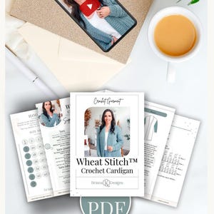 May include: A flat lay featuring a smartphone displaying a video, a stack of crochet pattern instructions, and a cup of tea. The pattern instructions are for a "Wheat Stitch Crochet Cardigan" by Briana K Designs, available as a PDF.