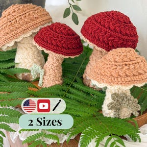 May include: Four crocheted mushroom figures in two sizes, featuring textured caps in shades of tan and deep red with cream-colored stalks. Each mushroom has a small green leaf accent at the base. The image includes a graphic with the text 2 Sizes.