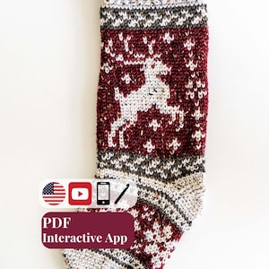 May include: A knitted holiday stocking featuring a white reindeer motif on a deep red background with speckled cream accents at the cuff, heel, and toe. A brown leather hanging loop is attached to the top. Text includes PDF Interactive App.