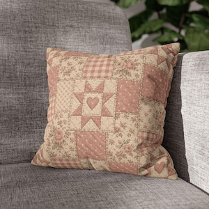 May include: A square throw pillow featuring a patchwork design in shades of dusty rose and cream. The pattern includes floral prints, gingham checks, and polka dots, with a central star motif containing a small heart at its center.