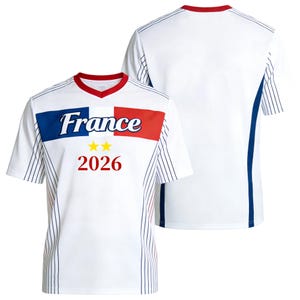 Op de afbeelding: Een wit T-shirt met korte mouwen, een rode V-hals en blauwe en rode zijpanelen met dunne verticale strepen. Op de borst staat een blauwe, witte en rode horizontale band met het woord France, twee gele sterren en het jaartal 2026.