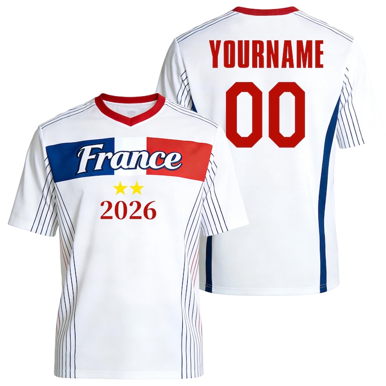 Op de afbeelding: Een wit shirt met korte mouwen, een rode kraag en blauwe en rode zijpanelen met dunne verticale strepen. De voorkant toont het woord France, twee gele sterren en het jaartal 2026. De achterkant toont de tekst YOURNAME en het nummer 00.