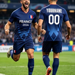 K&ouml;nnte beinhalten: Ein dunkelblaues Fu&szlig;balltrikot und Shorts mit der Aufschrift FRANCE 2026 auf der Vorderseite, einer kleinen franz&ouml;sischen Flagge sowie der Aufschrift YOURNAME mit der Nummer 00 auf der R&uuml;ckseite. Das Set umfasst passende Socken und Fu&szlig;ballschuhe.