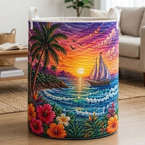 May include: A cylindrical laundry hamper featuring a vibrant quilted print of a tropical sunset over the ocean. The design includes a sailboat, palm trees, and colorful hibiscus flowers in shades of pink, orange, and yellow with white handles.