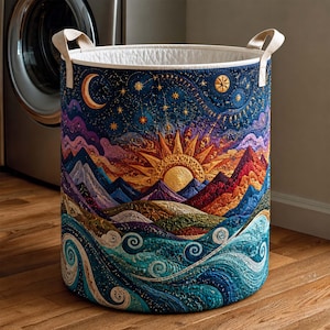 May include: A cylindrical fabric laundry hamper featuring a quilted exterior with a vibrant celestial and landscape design. The pattern displays a golden sun, a crescent moon, starry skies, purple mountains, and swirling teal ocean waves with two handles.