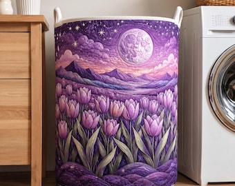 May include: A cylindrical laundry hamper featuring a quilted fabric exterior with a vibrant purple landscape print. The design displays a field of purple tulips in the foreground, rolling mountains, and a large full moon in a starry night sky.