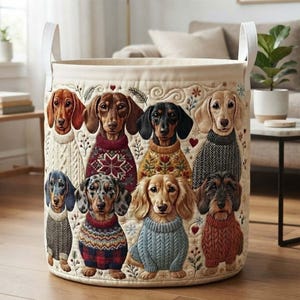 May include: A cylindrical fabric storage basket featuring a quilted design with eight dachshunds wearing various patterned sweaters. The dogs are depicted in different colours and coat textures, surrounded by small embroidered floral and heart motifs.