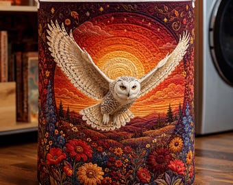 May include: A cylindrical laundry hamper featuring a quilted design of a white owl in flight against a sunset background. The scene includes a vibrant orange and red sky, rolling hills, and a foreground filled with colorful flowers and foliage.