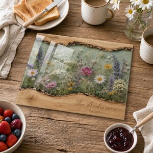 May include: A rectangular wooden serving board featuring a central resin inlay filled with pressed wildflowers in shades of pink, yellow, white, and blue. The wood has natural live edges, and the text "The Andersons Est. 2026" is engraved on the surface.