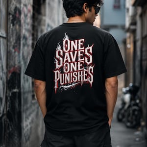 Pode incluir: Uma t-shirt preta de manga curta com um gr&aacute;fico nas costas apresentando o texto branco e vermelho "ONE SAVES ONE PUNISHES" numa fonte g&oacute;tica estilizada, acentuado com detalhes de chamas e um elemento gr&aacute;fico afiado na parte inferior.