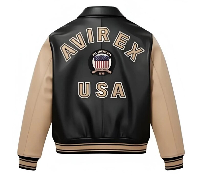 May include: A black and tan varsity jacket featuring the text AVIREX and USA in beige lettering on the back. A circular patch with a United States flag graphic and the text ALL AMERICAN 1975 is centred between the words on the back panel.