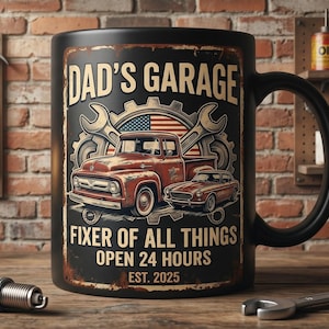 Könnte beinhalten: Schwarze Keramik-Tasse mit Vintage-Design, das einen roten Pickup und ein Auto, Schraubenschlüssel und die amerikanische Flagge zeigt. Der Text lautet "DAD'S GARAGE FIXER OF ALL THINGS OPEN 24 HOURS EST. 2025."