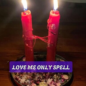 Puede incluir: Dos velas rojas altas con llamas encendidas, conectadas por un hilo rojo fino, se mantienen erguidas en una bandeja metálica circular llena de pétalos de flores secas y hierbas. Una banda rectangular morada muestra el texto LOVE ME ONLY SPELL.