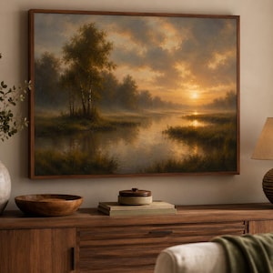 Puede incluir: Un cuadro de paisaje rectangular en un marco de madera que representa una puesta de sol sobre un río tranquilo con árboles y orillas cubiertas de hierba. La escena muestra una cálida luz dorada que se refleja en el agua y nubes suaves.