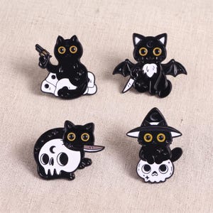 May include: Four black cat enamel pins with yellow eyes. One holds a gun on white clouds, one has bat wings and a knife, one sits on a white skull holding a knife, and one wears a witch hat while sitting on a white skull with a crescent moon.