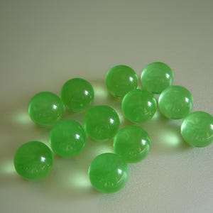 Peut inclure: Un ensemble de sphères vertes translucides, chacune avec une surface légèrement irrégulière, disposées sur un fond clair. Les sphères ont un aspect brillant, reflétant la lumière et créant des reflets.