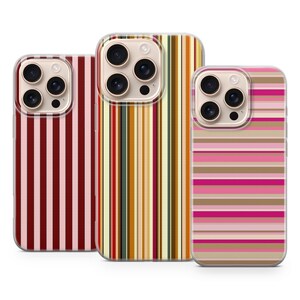 May include: Three phone cases with colorful striped designs. The cases feature vertical stripes in shades of red, brown, and pink, as well as a case with horizontal stripes in pink, brown, and beige. Each case has a camera cutout.
