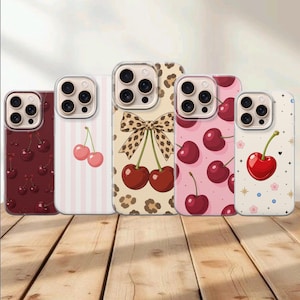 Op de afbeelding: Vijf smartphonehoesjes met diverse ontwerpen: een donkerrood hoesje met kersen, een lichtroze gestreept hoesje met twee kersen, een beige luipaardprint hoesje met een strik en kersen, een roze hoesje met kersen en een wit hoesje met een kers.