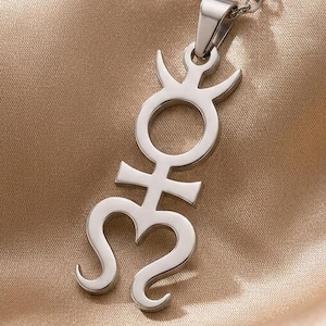 May include: A silver-toned metal pendant necklace featuring a vertical, stylized symbol with a circular center, a crescent top, and a curved, bifurcated base. The pendant hangs from a delicate silver-toned chain link, showcasing a polished finish.