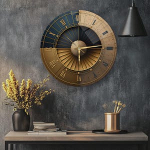 Puede incluir: Un reloj de pared circular con un dise&ntilde;o dividido en una mitad superior azul oscuro y una mitad inferior de color oro met&aacute;lico. La esfera muestra n&uacute;meros romanos, un patr&oacute;n central de rayos de sol y manecillas doradas finas.