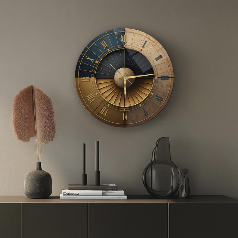 Puede incluir: Un reloj de pared circular con un dise&ntilde;o dividido en una mitad azul oscuro y otra mitad de color tostado claro. La esfera muestra n&uacute;meros romanos dorados y manecillas finas doradas. El centro tiene un elemento circular con l&iacute;neas.