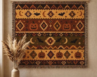 May include: A woven throw blanket featuring a repeating pattern of jack-o'-lanterns, crescent moons, and bats in shades of orange, brown, and olive green. The textile has a fringed edge and displays geometric motifs across its horizontal bands.
