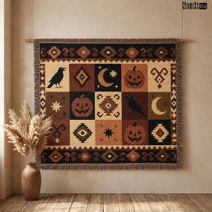 May include: A woven throw blanket featuring a grid pattern of black, tan, and brown squares. The design includes illustrations of black crows, orange jack-o'-lanterns, crescent moons, stars, and geometric diamond shapes with a fringed border.