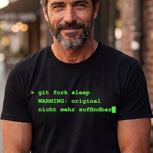 Può includere: T-shirt nero con testo verde: "> git fork sleep WARNING: original nicht mehr auffindbar". La maglietta è a maniche corte e ha un girocollo. Il testo è in un carattere in stile terminale del computer.