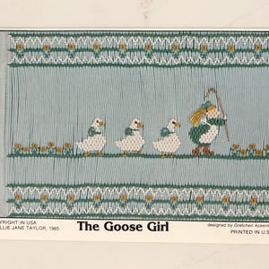 May include: A vintage needlepoint pattern titled "The Goose Girl." The design features a girl with a staff and three geese, set against a light blue background with floral and geometric borders. The text "The Goose Girl" is displayed at the bottom.