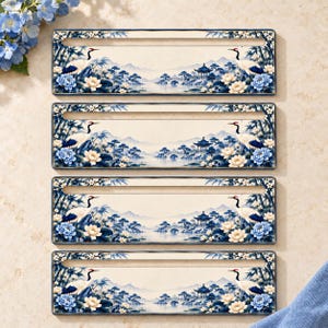 May include: Four rectangular ceramic tiles featuring a blue and white landscape illustration. The design depicts cranes, blooming flowers, bamboo stalks, a pagoda, and a bridge over water, with a horizontal slot cut into each tile.