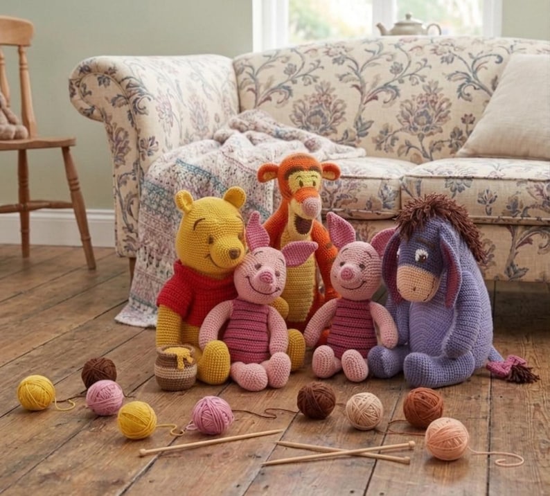May include: A collection of handmade Winnie the Pooh character plush toys, including Winnie the Pooh, Piglet, Tigger, Eeyore, and two Piglets. The toys are made of yarn and are arranged on a wooden floor with yarn balls and knitting needles.